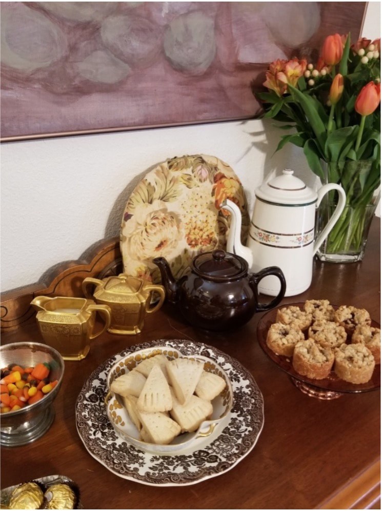 A tea set with traditional snacks and flowers on a table.