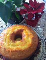 A moist bundt cake glazed with a shiny orange topping on a glass plate.