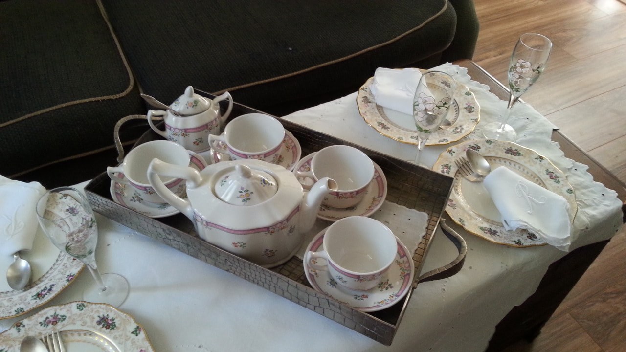 Elegant tea set with cups, saucers, and teapot on a wooden tray.