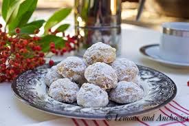 Plate of powdered sugar-coated cookies with red berries in the background.