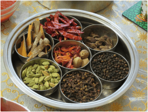 A traditional Indian spice box with various whole spices.