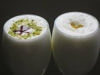 Two glasses of traditional Indian lassi with garnishes.