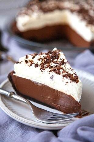 A slice of chocolate cream pie topped with whipped cream and chocolate shavings.