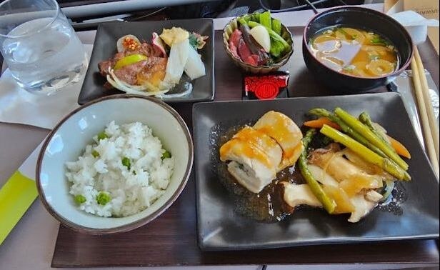 A Japanese meal with rice, grilled chicken, salad, and soup.