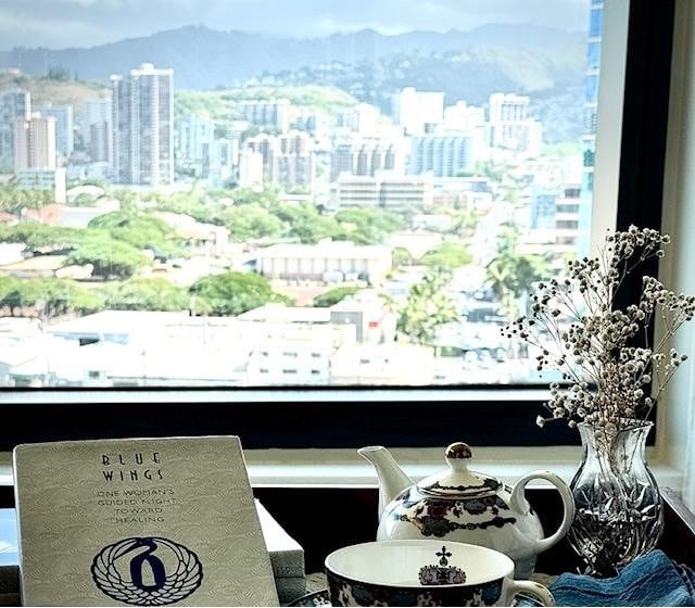 Cozy tea setup by a window overlooking a cityscape with greenery.