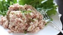 Close-up of creamy tuna salad garnished with herbs on a white plate.