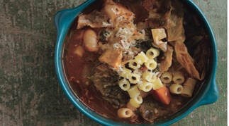 Hearty bowl of vegetable soup with pasta and herbs.
