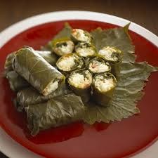 Stuffed grape leaves arranged on a red plate.