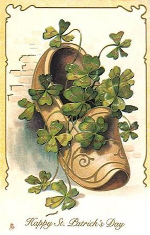 An old shoe filled with green clovers against a textured wall.