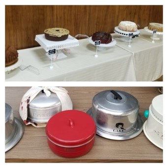A table displaying various cakes and covered desserts in different containers.