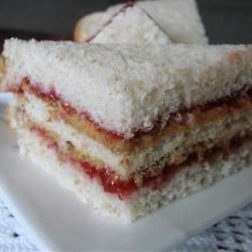 Close-up of layered white bread sandwich with jam filling.