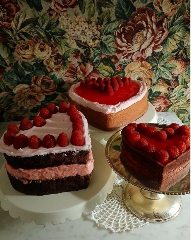 Heart-shaped cakes with raspberries on stands.