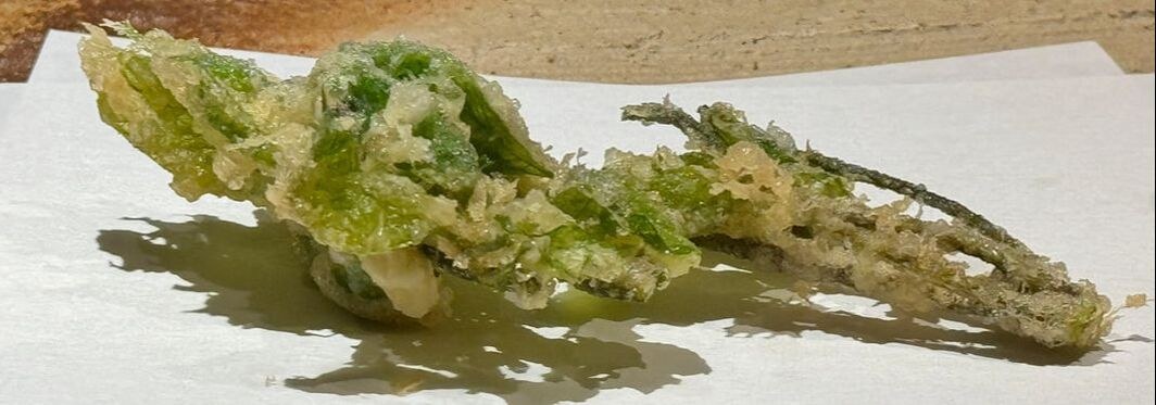 Close-up of crispy fried green leaves on a white surface.