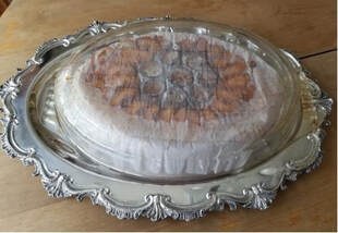Elegant silver platter with a covered dessert inside.