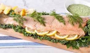 Fresh salmon fillet garnished with lemon slices and dill on a wooden board.