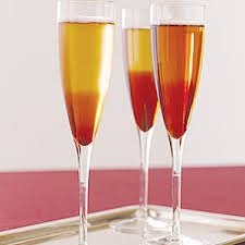 Three champagne flutes filled with amber-colored drink on a tray.