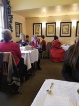 People dining in a cozy, warmly lit restaurant with framed artwork on walls.