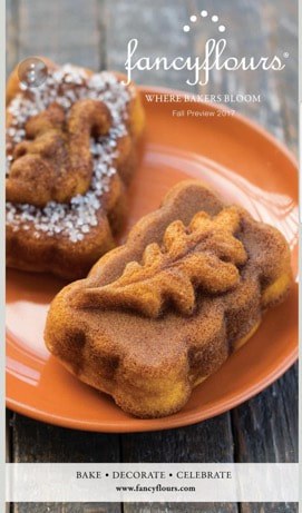Decorative autumn-themed pastries topped with powdered sugar on an orange plate.