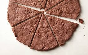 Uncooked dough rolled and sliced into triangular pieces on a white surface.