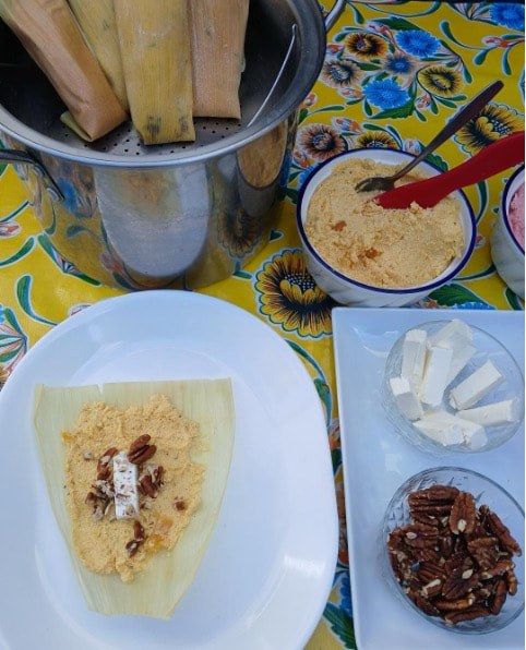 Crepe with cream and nuts on a colorful tablecloth with accompaniments.