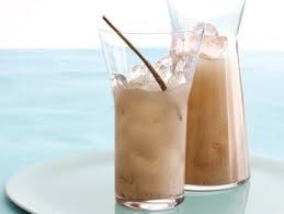 Two glasses of iced coffee with straws by the sea.