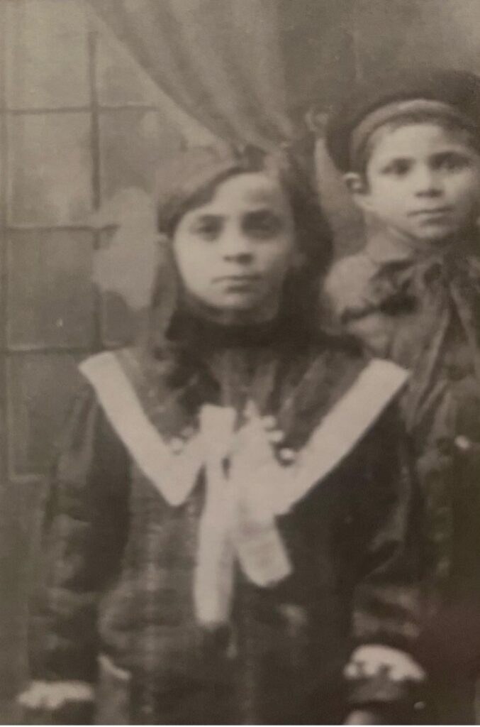 Black and white photo of a young girl in vintage clothing.