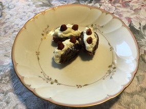 Three chocolate and cream dessert bites on a decorative plate.