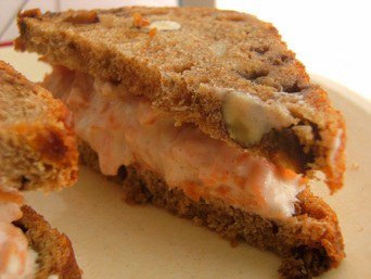 Close-up of a sandwich with melted cheese and tomato filling.