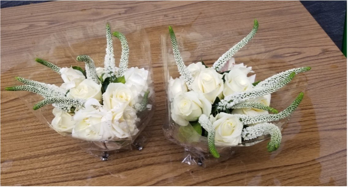 Two elegant white floral arrangements on a wooden surface.