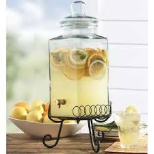 Glass dispenser with lemon-infused water and slices on a stand.