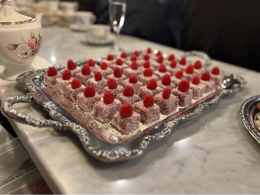 Elegant dessert topped with raspberries on a silver tray.