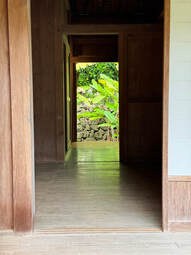 View through a wooden hallway opening to a lush garden.