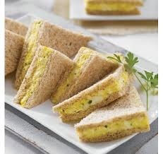 Triangular sandwiches with a yellow filling on a white plate.