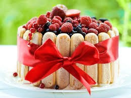 A festive dessert decorated with ladyfingers, berries, and a red ribbon.