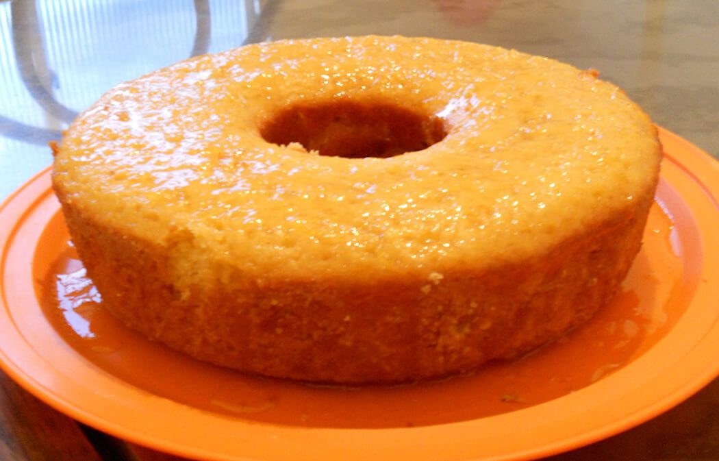 A plain glazed bundt cake on an orange plate.