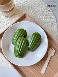 Three green madeleine-shaped desserts on a white plate.