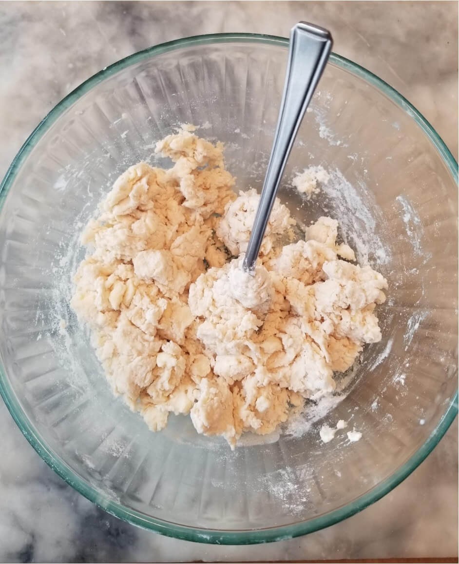 Mixing dough in a glass bowl with a spoon.