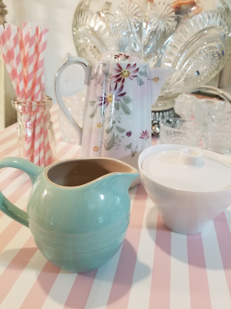 Pastel-colored ceramic pitchers and a cup on a checkered tablecloth.