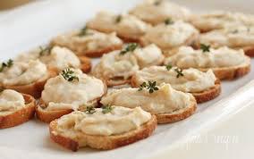 Mini toasted bread slices topped with creamy spread and herbs.