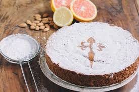 Powdered sugar cake with almonds and citrus fruits on a rustic table.