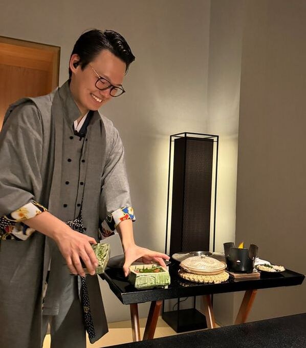 A man preparing food at a table with a smile.