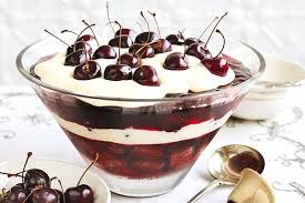 Layered cherry dessert with whipped cream and fresh cherries on top.