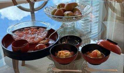 Japanese hot pot with tofu and dipping sauces on a table by the window.