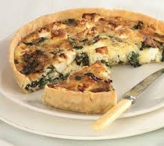 A slice of spinach and cheese quiche on a plate with a knife.