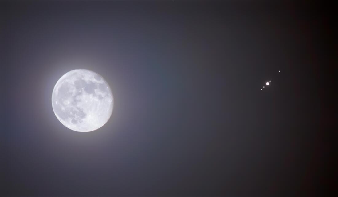 Bright full moon illuminating the night sky with a small airplane nearby.
