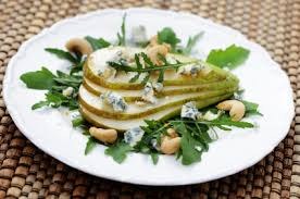 Grilled pear salad with greens, blue cheese, and nuts on a white plate.