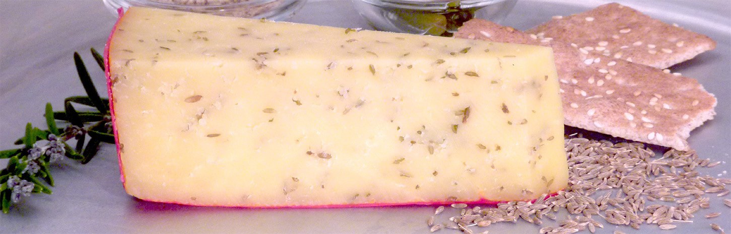 Close-up of herb-infused cheese with a red rind.