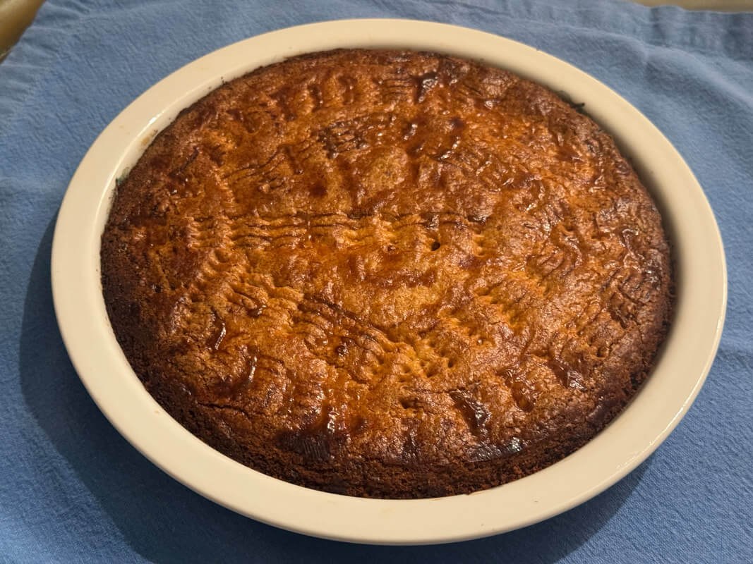 A freshly baked pie with a golden crust in a white ceramic dish.