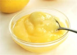 A bowl of smooth lemon curd with a spoon.