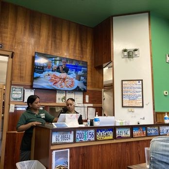 Two staff members wearing masks behind a counter in a cozy restaurant.